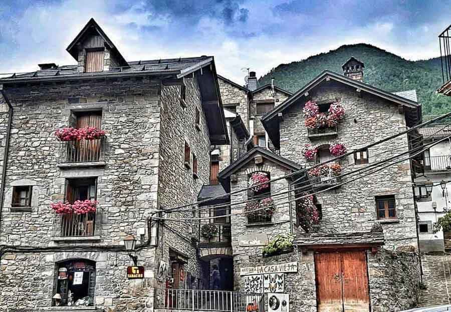 Casas de piedra con balcones llenos de flores en un pueblo del Pirineo, ideal para que ver en Ordesa y Monte Perdido.