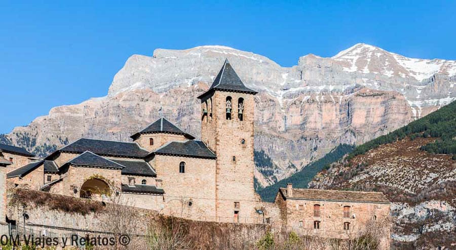 Iglesia y casas de piedra en Torla con las montañas al fondo, un imprescindible de que ver en Ordesa y Monte Perdido.