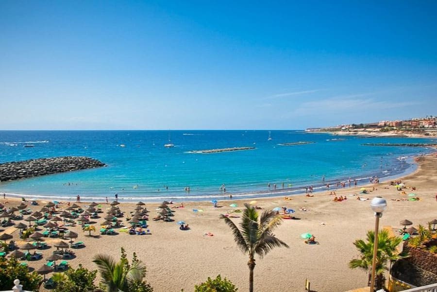 Playa de las Américas en Tenerife con arena dorada y mar tranquilo, una de las zonas más populares donde alojarse en Tenerife.