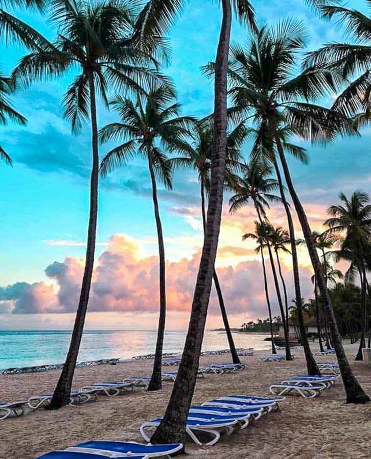 Atardecer con palmeras y tumbonas frente al mar, una postal perfecta de las playas de Samaná.