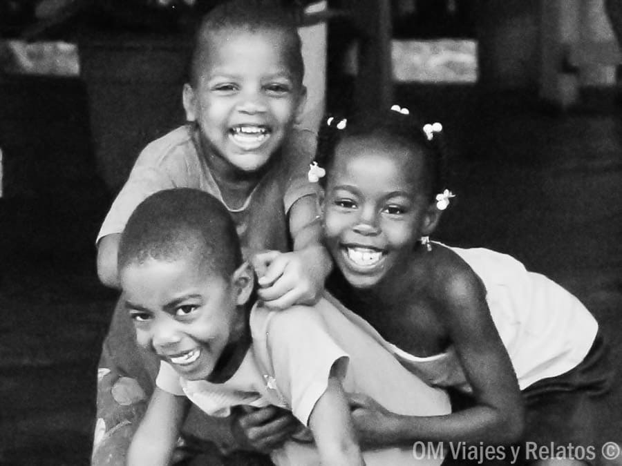 Tres niños riendo en una escena cotidiana en blanco y negro, reflejo del lado más auténtico cerca de las playas de Samaná.