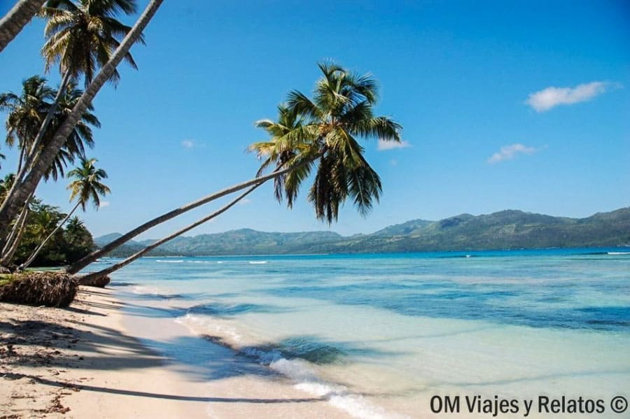 Vista de Playa Bonito con palmeras inclinadas, mar turquesa y montañas al fondo, una de las playas de Samana más bonitas.