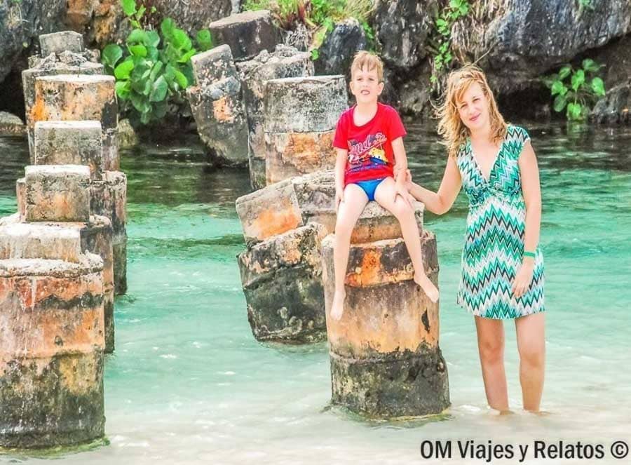 Servidora e hijo en Playa Rincón, con agua turquesa y rocas alrededor, disfrutando de una de las playas de Samaná más bonitas.