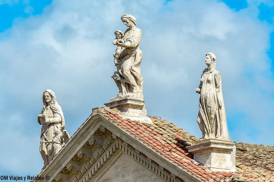 Estatuas de piedra en el tejado de una iglesia de Roma bajo un cielo azul, un detalle curioso en que ver en Roma en 4 días.
