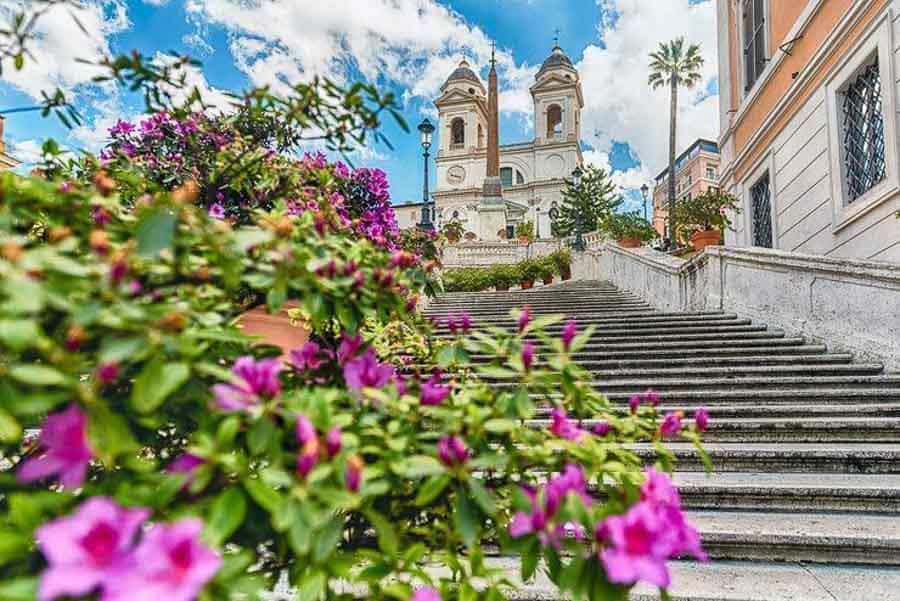 Escalinata de la Plaza de España con flores en primer plano y la iglesia de Trinità dei Monti al fondo, un clásico en que ver en Roma en 4 dias.