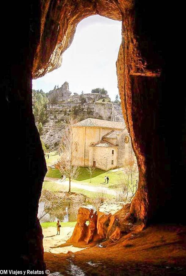 Vista de una ermita desde el interior de una cueva, una imagen con encanto para descubrir rutas en Castilla y Leon.
