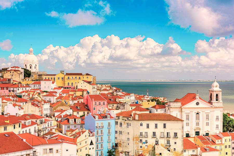 Vista panorámica del barrio de Alfama con el río Tajo al fondo, una de las zonas con más encanto para decidir donde alojarse en Lisboa.