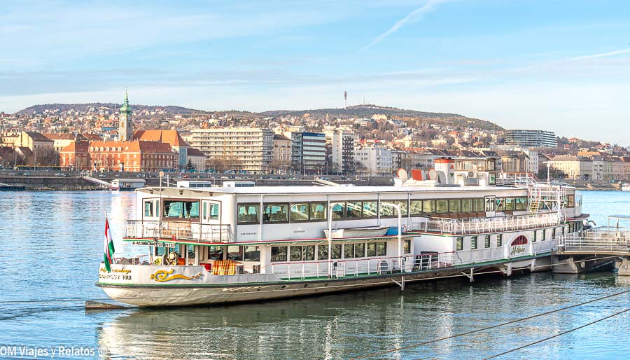Barco turístico amarrado en el Danubio con vistas a Budapest al fondo, una imagen ideal para ilustrar un paseo en barco Budapest.