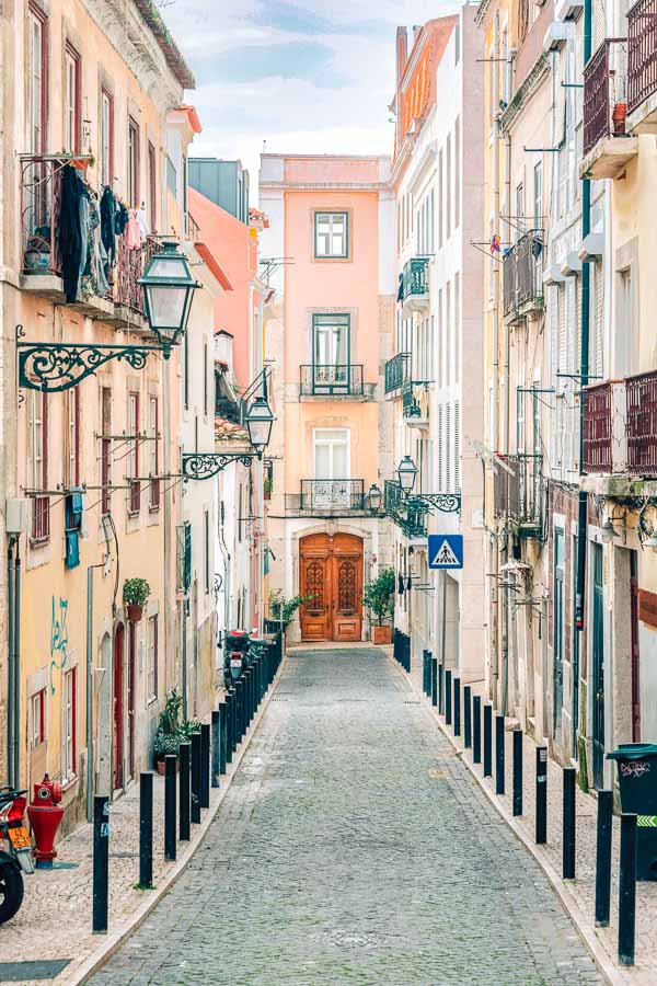 Calle estrecha con fachadas y balcones en Barrio Alto, una zona animada y céntrica para decidir donde alojarse en Lisboa.