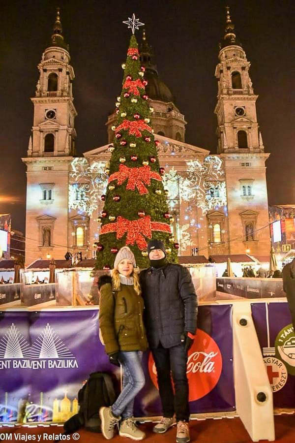 Foto en pareja de OM Viajes y Relatos frente a la Basílica de San Esteban y el árbol de Navidad, una imagen muy especial de un viaje a Budapest por libre en invierno.