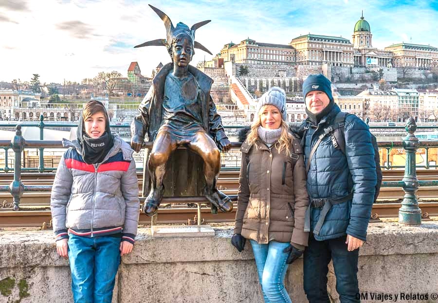 Foto familiar de OM Viajes y Relatos junto a la estatua de la Pequeña Princesa con el Castillo de Buda al fondo, una imagen muy especial de un viaje a Budapest por libre