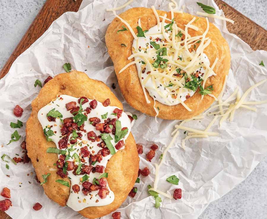 Lángos con crema agria, queso y bacon, una comida típica para disfrutar durante un viaje a Budapest por libre.