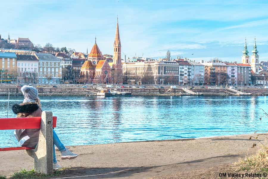 Servidora sentada frente al Danubio con vistas a Buda al otro lado del río, una imagen perfecta para completar un paseo en barco Budapest.