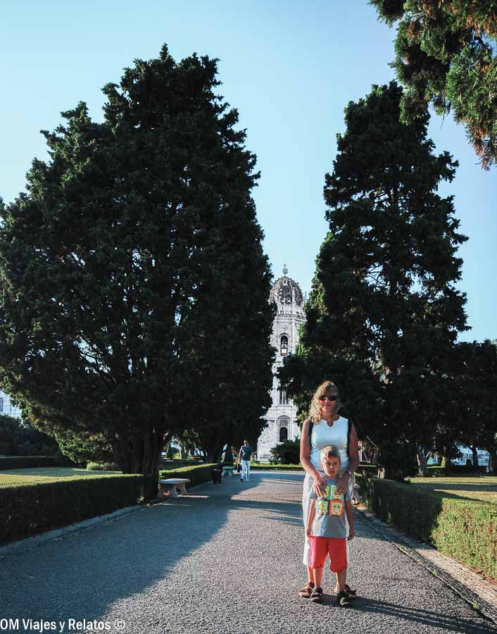 Foto mía y de mi hijo paseando por los jardines de Belém con el Monasterio de los Jerónimos al fondo, una zona monumental a considerar al decidir donde alojarse en Lisboa.