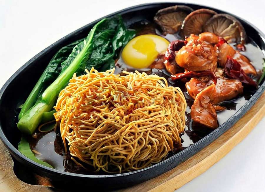 Probar unos crujientes fideos malayos con salsa y verduras es una experiencia imprescindible para descubrir donde comer en Kuala Lumpur.
