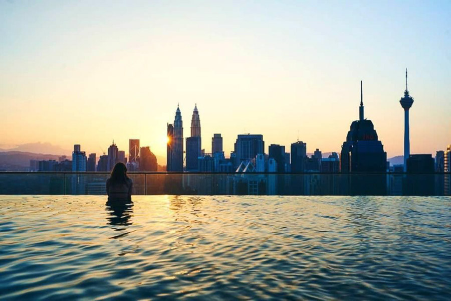 Una servidora disfrutando de la infinity pool del KLCC Suites by Colony con vistas al skyline de Kuala Lumpur al atardecer.