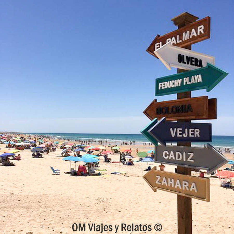 Carteles señalando destinos junto a una de las playas mas bonitas de Cádiz con ambiente veraniego.
