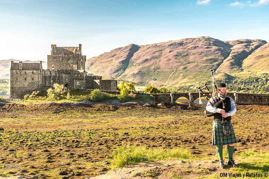Gaitero escocés frente al castillo de Eilean Donan, uno de los lugares imprescindibles que ver en Escocia en 7 días.