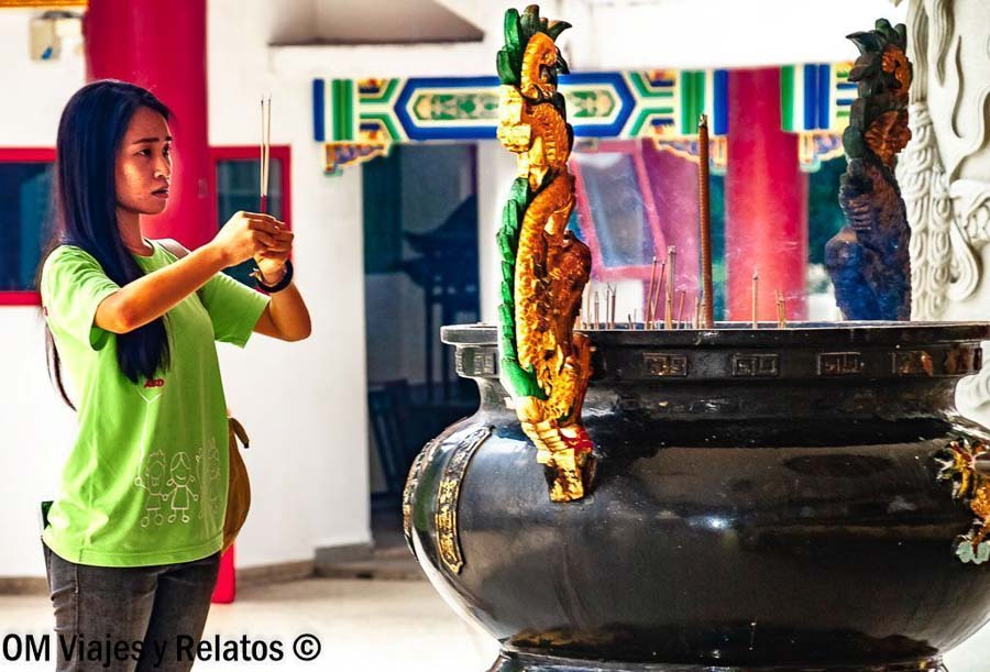 Mujer realizando una ofrenda con incienso en un templo chino de Kuala Lumpur, una experiencia cultural que ver en Kuala Lumpur en 2 dias.