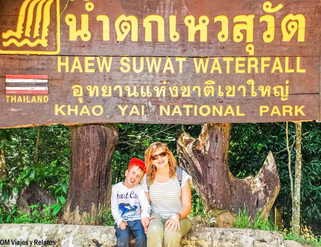 Foto mía y de mi hijo posando junto al cartel de Haew Suwat Waterfall, una de las cascadas más famosas del Parque Nacional de Khao Yai en Tailandia.