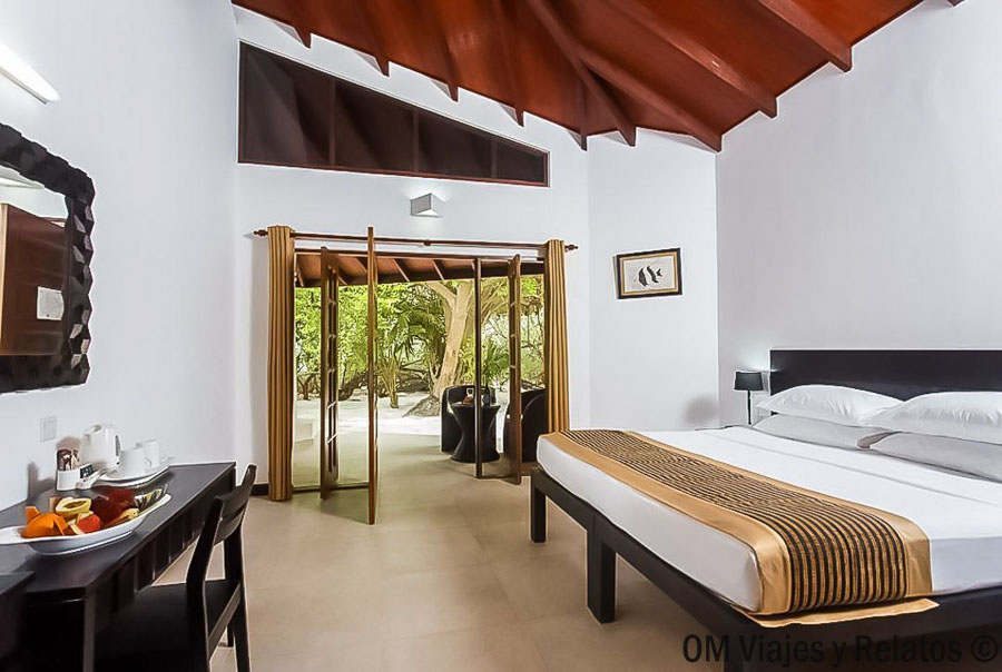 Habitación de Embudu Village Resort con terraza abierta a la vegetación tropical, una opción a valorar para decidir que hotel elegir en maldivas.