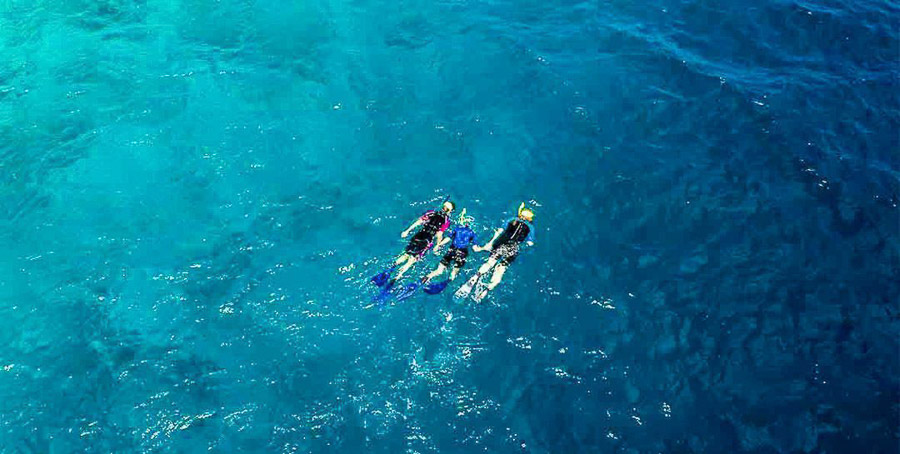 Foto familiar haciendo snorkel en aguas cristalinas de Maldivas, una experiencia clave para decidir que hotel elegir en maldivas.