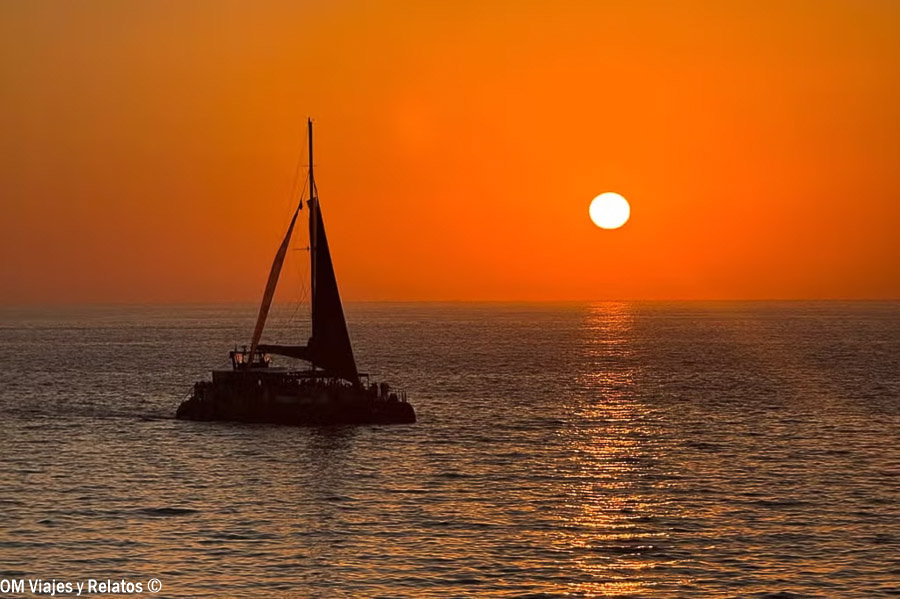 Velero navegando al atardecer frente a la costa de Cádiz, una de las imágenes más espectaculares que ver en Cádiz en un día.