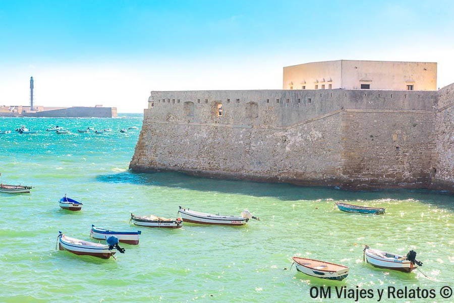 Castillo de San Sebastián y embarcaciones tradicionales en la bahía, uno de los lugares imprescindibles que ver en Cádiz en un día.