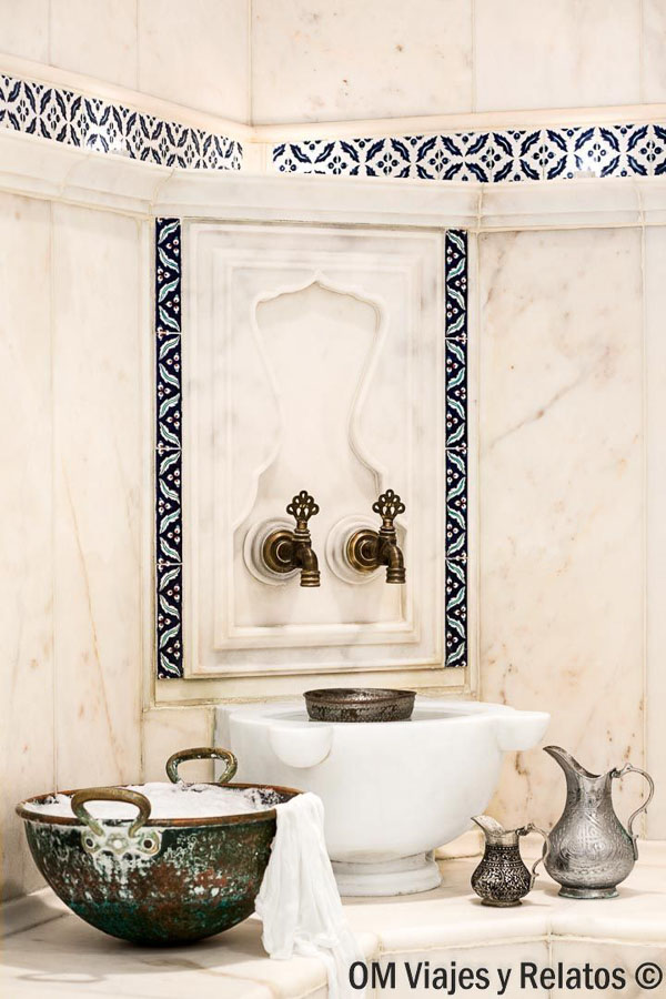 Interior de un hammam turco con mármol, grifos tradicionales y utensilios de baño, una experiencia relajante para incluir en que ver en Estambul en 3 dias.