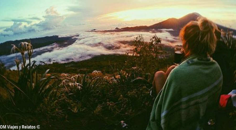 Servidora contemplando el amanecer desde el volcán Batur con vistas a las nubes y montañas, una experiencia imprescindible al planificar que ver y hacer en Bali por zonas.