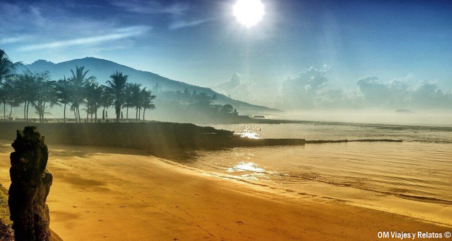 Playa de Bali al amanecer con palmeras, mar en calma y luz dorada, una escena tranquila para incluir entre las mejores playas de Bali.