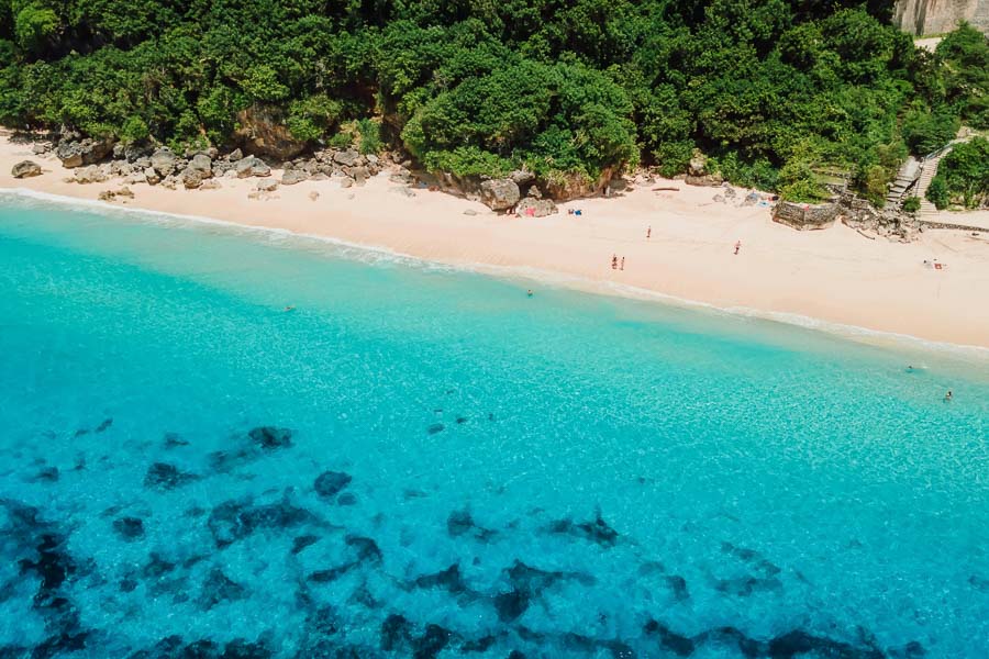 Vista aérea de Melasti Beach, con arena blanca, aguas turquesas y vegetación tropical, una de las mejores playas de Bali.