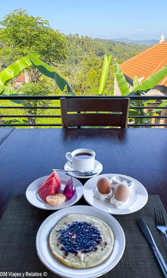 Desayuno con fruta, huevos, café y tortita con vistas a la vegetación tropical de Bali