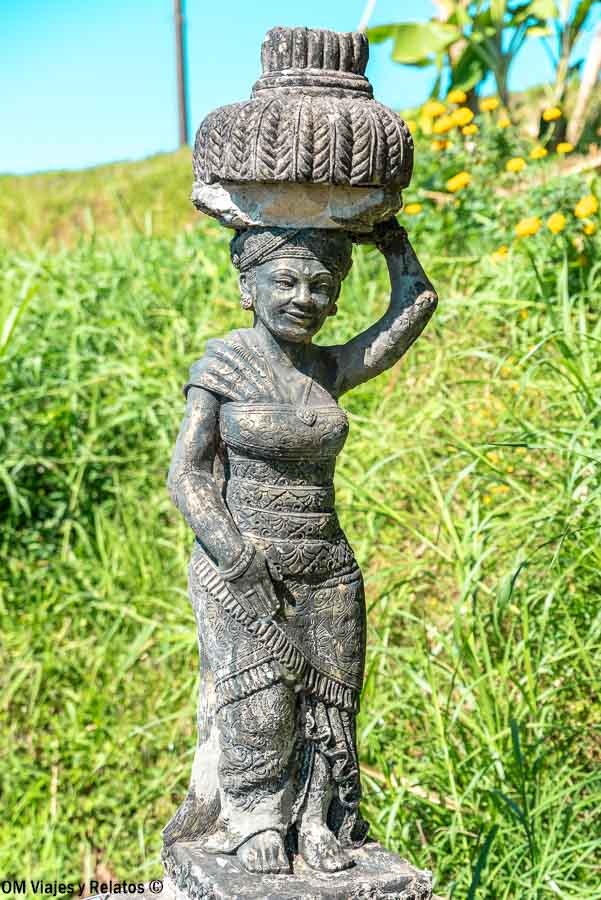 Escultura de una mujer balinesa portando una ofrenda tradicional sobre la cabeza