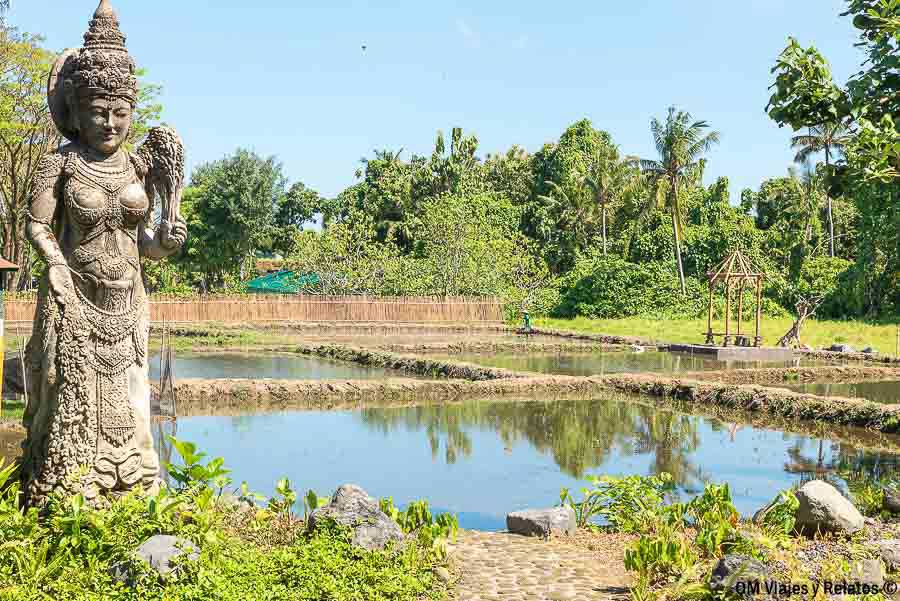 Escultura tradicional balinesa junto a campos de arroz y vegetación tropical en Bali