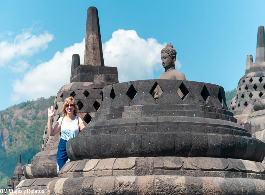 Servidora junto a una estupa y una figura de Buda en el templo budista de Borobudur