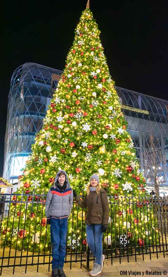 Servidora y nuestro hijo frente a un gran árbol de Navidad iluminado en Budapest