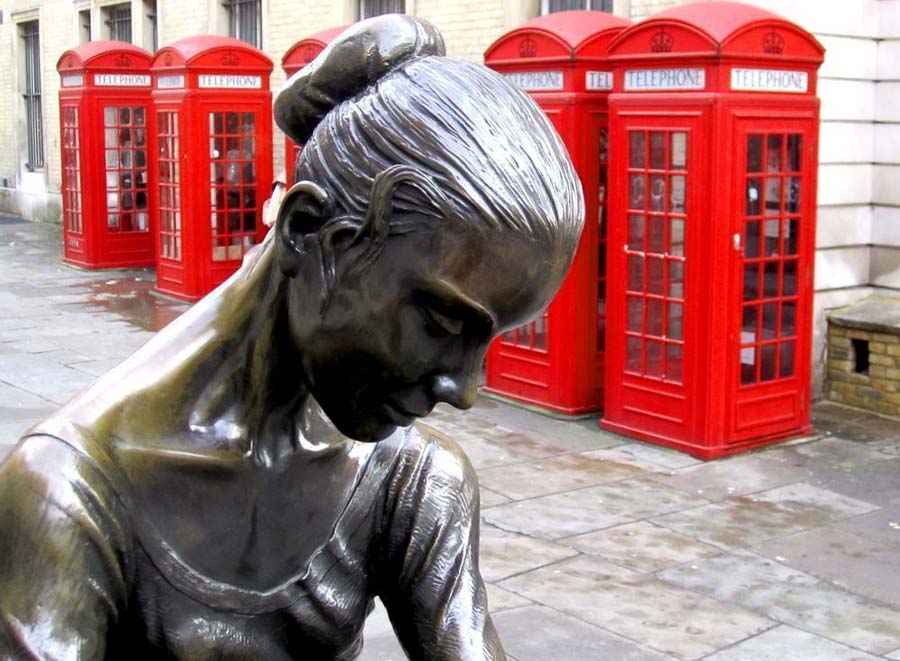 Estatua de una bailarina junto a cabinas telefónicas rojas en Covent Garden, Londres