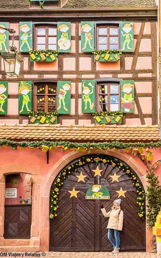 Servidora frente a una casa alsaciana decorada con motivos navideños y estrellas