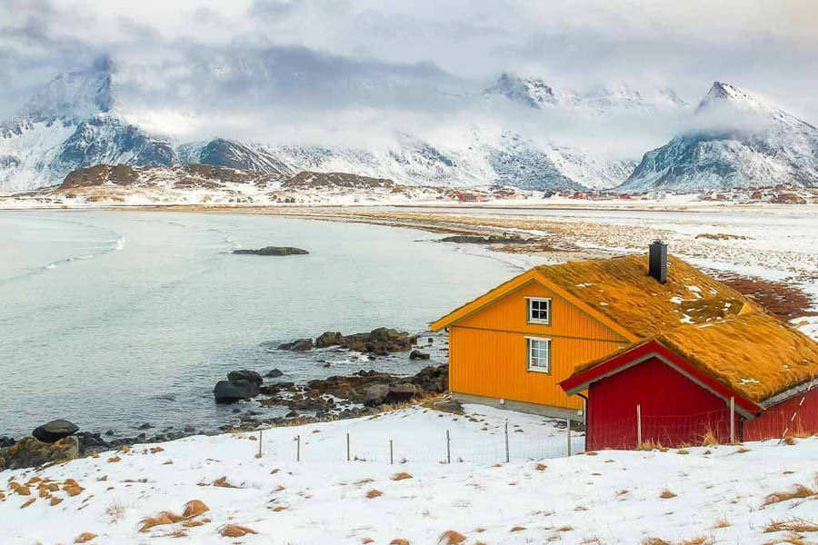 Casas tradicionales junto al mar y montañas nevadas en el norte de Noruega