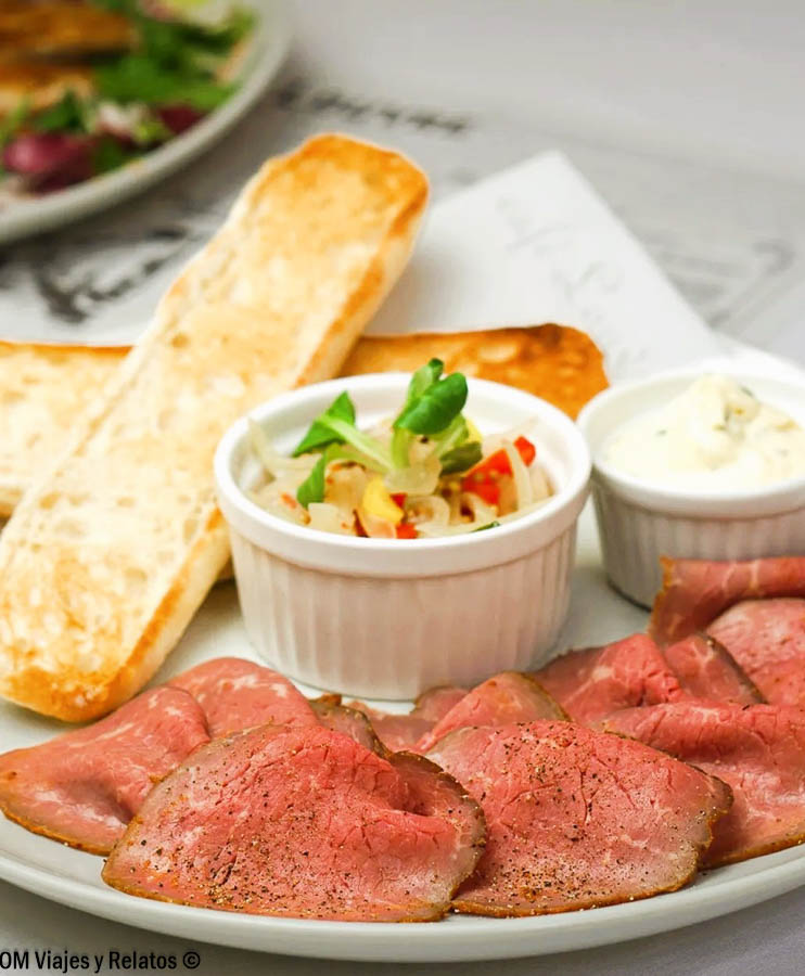 Plato de carne, pan y guarnición servido en el Café Louvre de Praga