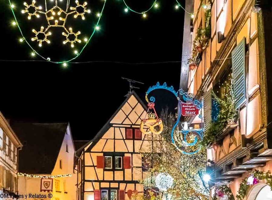 Calle de Alsacia iluminada en Navidad con casas de entramado de madera y decoración festiva