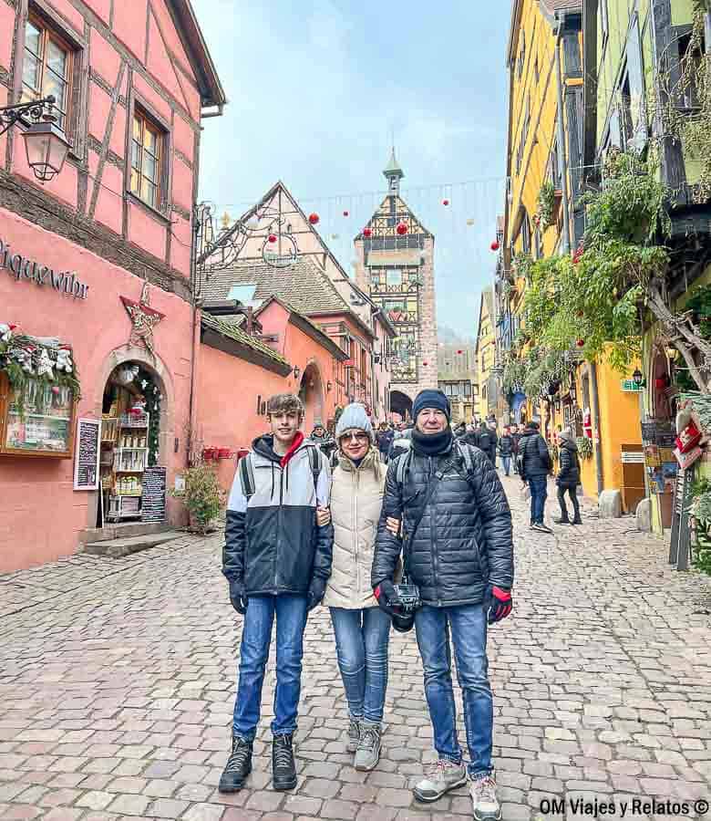 Foto familiar de OM Viajes y Relatos en Riquewihr durante la Navidad con el Dolder y casas tradicionales al fondo