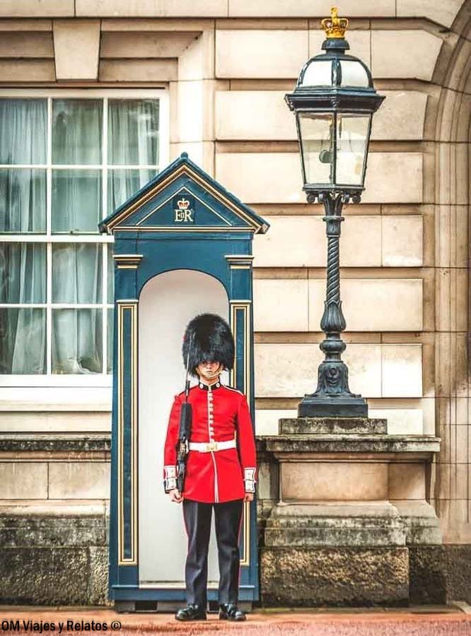 Guardia Real británica con uniforme rojo y gorro de piel negra junto a su garita en Londres