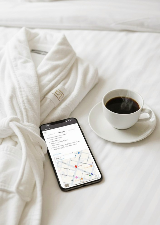 Albornoz, café y móvil sobre la cama de una habitación de hotel por horas