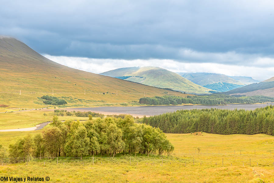 Paisaje de las Highlands con montañas, bosque y lago durante una ruta por Escocia