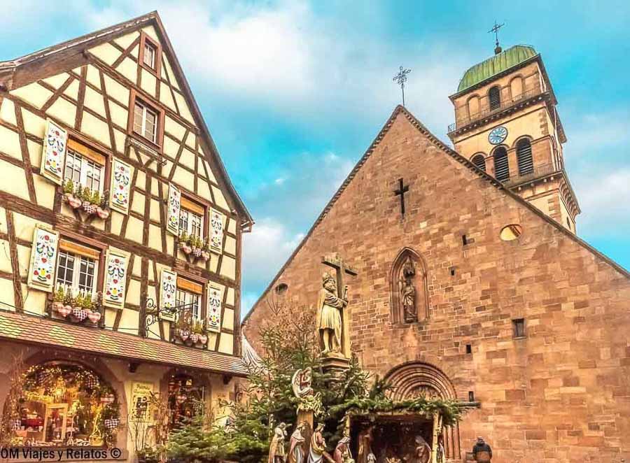 Iglesia Sainte-Croix de Kaysersberg junto a una casa alsaciana decorada en Navidad