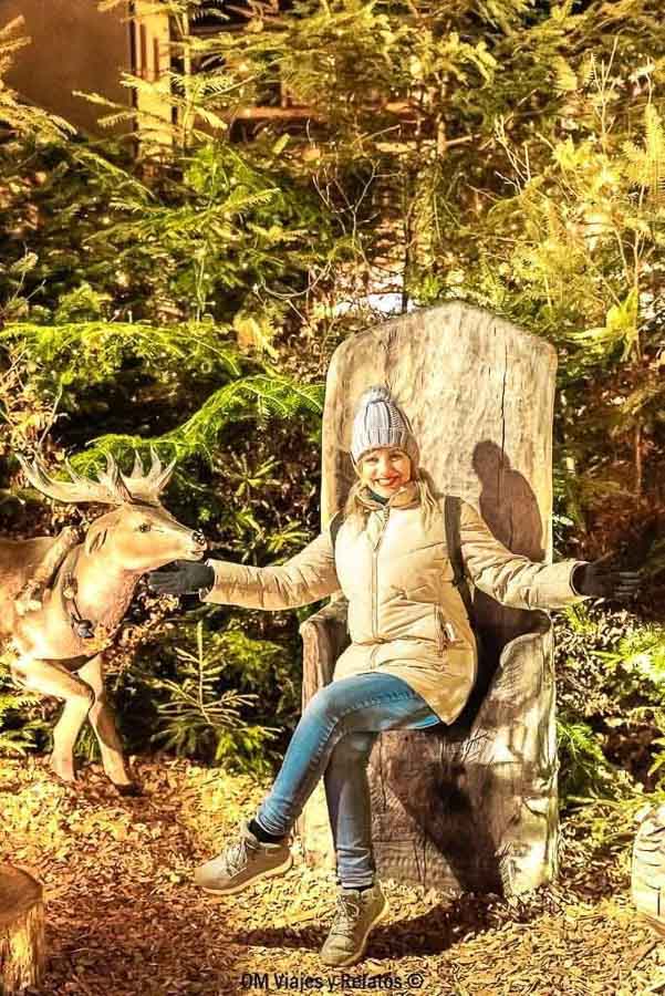 Foto mía sentada junto a un reno entre árboles de Navidad en Alsacia