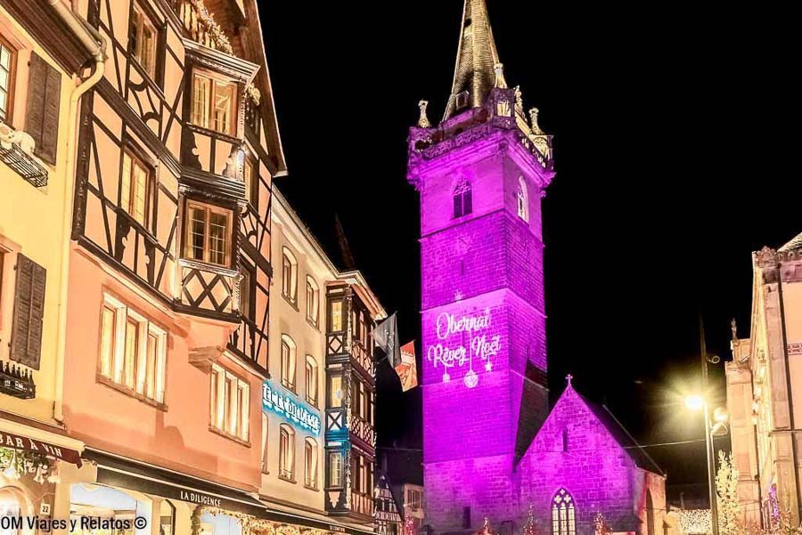 Torre del Kappelturm de Obernai iluminada en Navidad junto a casas tradicionales alsacianas