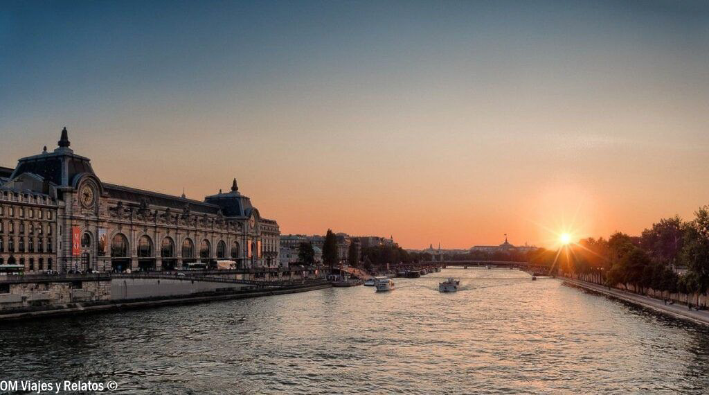 Atardecer sobre el río Sena en París, con el Museo de Orsay y varios barcos navegando por el río